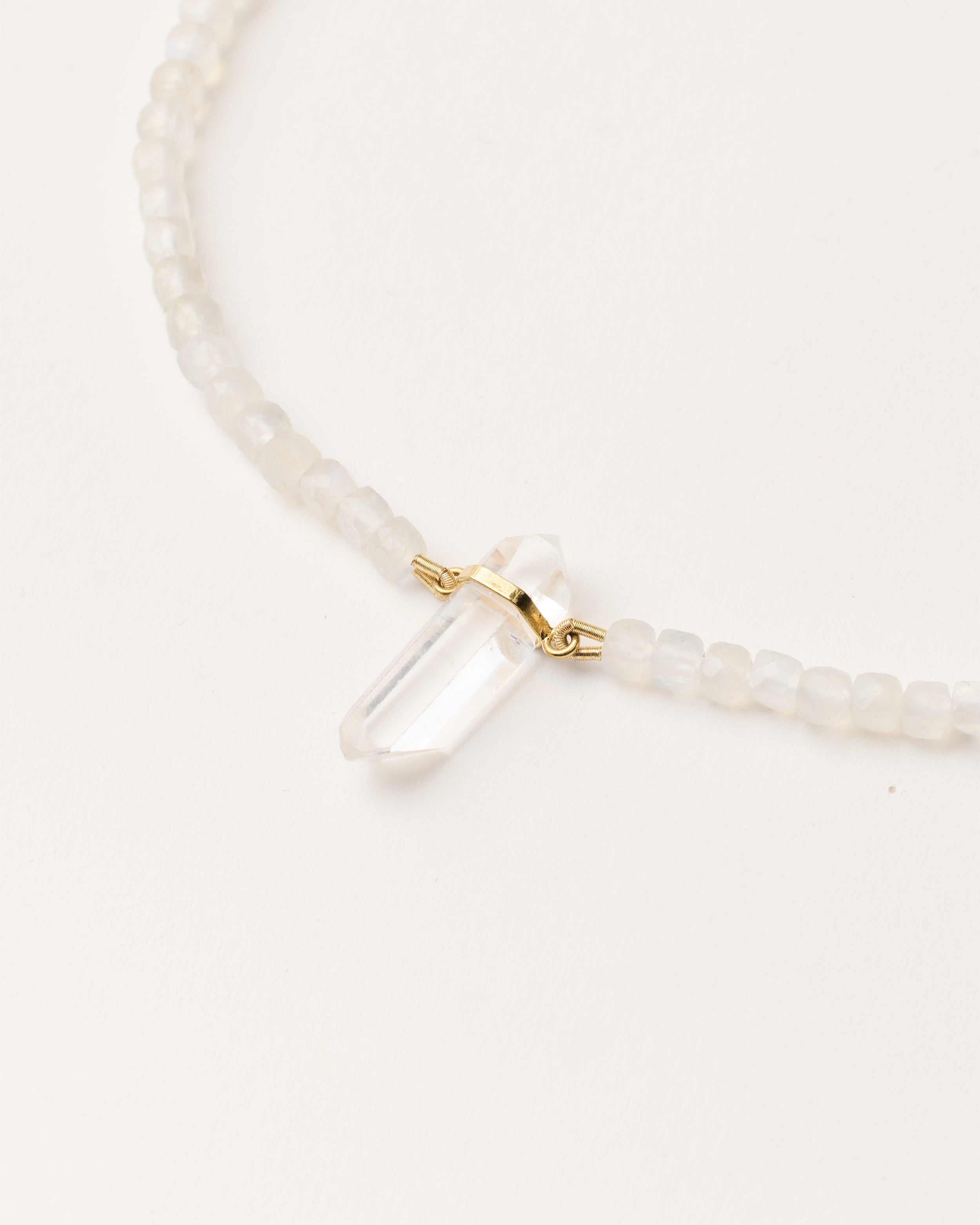 ENCARA LUNOR Moonstone necklace with raw polished quartz point pendant, gold 8 cm extension chain and clasp, arrowhead-shaped fantasy signature, and 4 mm faceted moonstone bead strand.