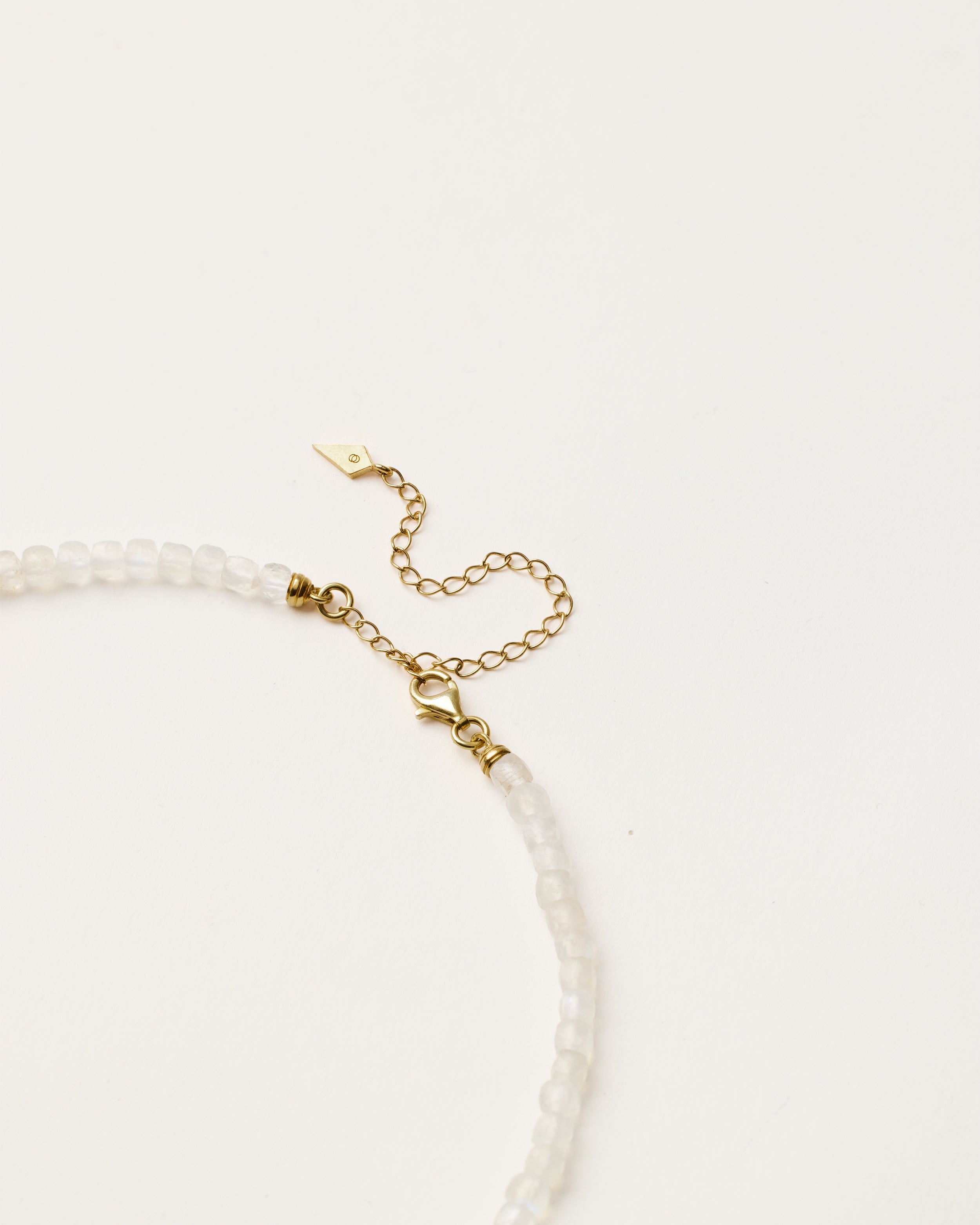 ENCARA LUNOR Moonstone necklace with raw polished quartz point pendant, gold 8 cm extension chain and clasp, arrowhead-shaped fantasy signature, and 4 mm faceted moonstone bead strand.