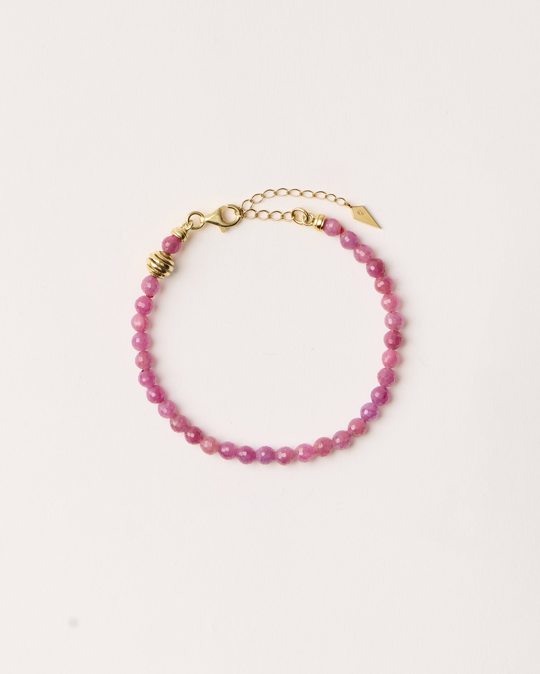 ETERNA CARMES Ruby bracelet with polished gold spiral bead, 4 cm extension chain and clasp, arrowhead-shaped fantasy signature, and 4 mm faceted ruby bead strand.