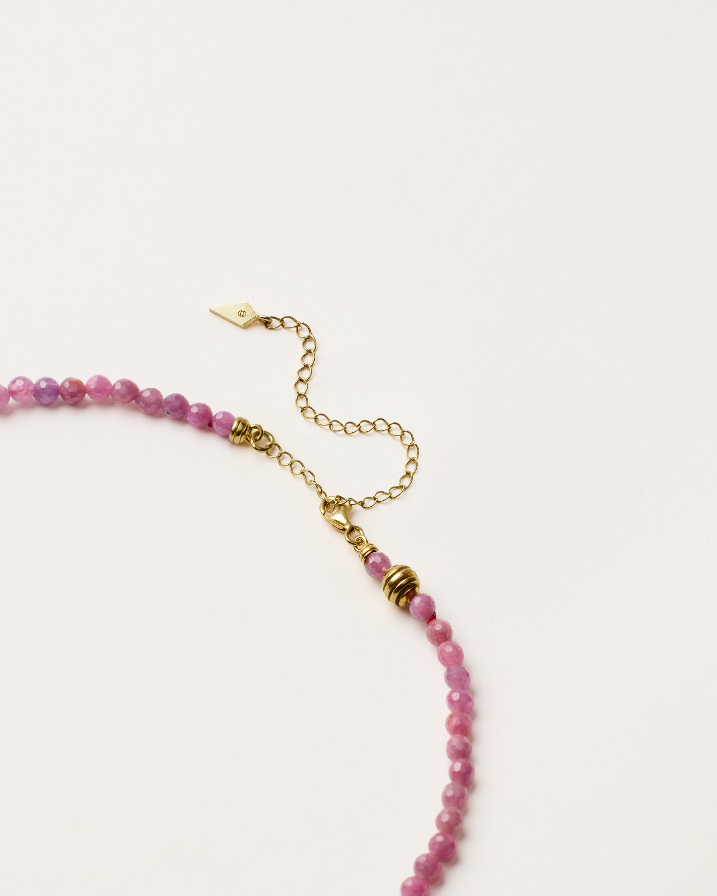 ETERNA CARMES Ruby necklace with polished gold spiral bead, 8 cm extension chain and clasp, arrowhead-shaped fantasy signature, and 4 mm faceted ruby bead strand.