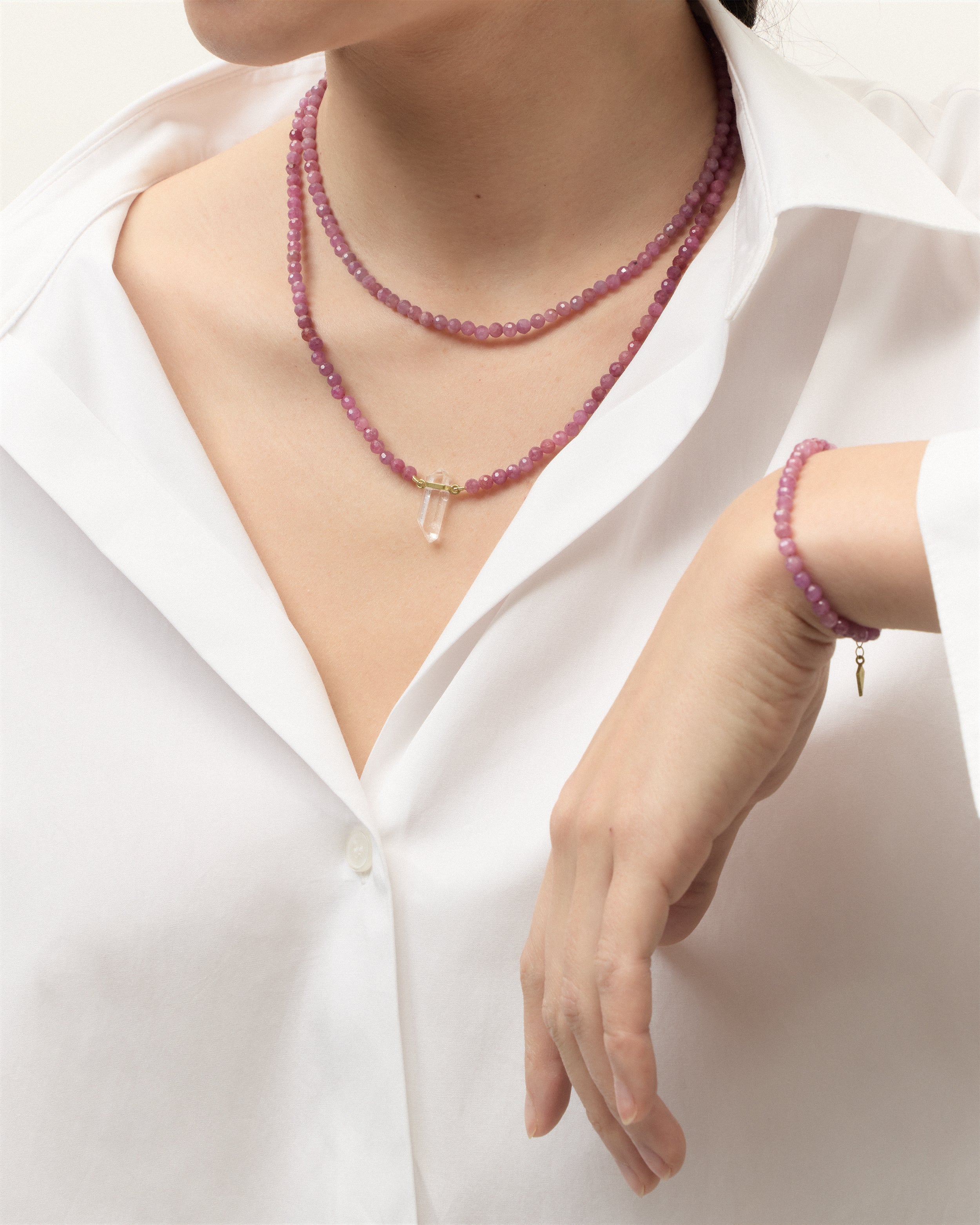 ENCARA / ETERNA CARMES Ruby necklaces and bracelet with polished gold spiral bead, extension chain and clasp, arrowhead-shaped fantasy signature, and 4 mm faceted ruby bead strand and raw polished quartz point pendant.