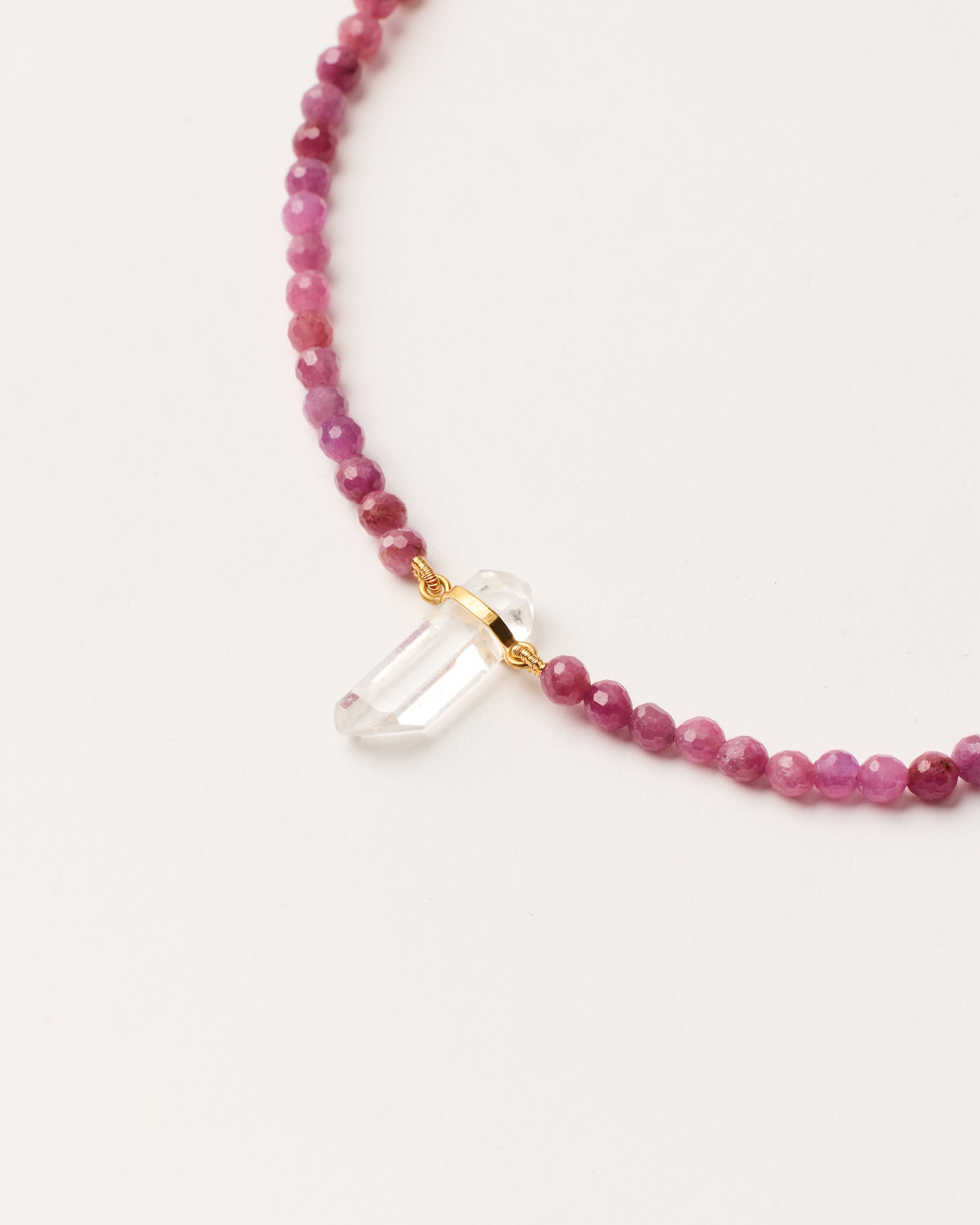 ENCARA CARMES Ruby necklace with raw polished quartz point pendant, gold-plated silver 8 cm extension chain and clasp, arrowhead-shaped fantasy signature, and 4 mm faceted ruby bead strand.