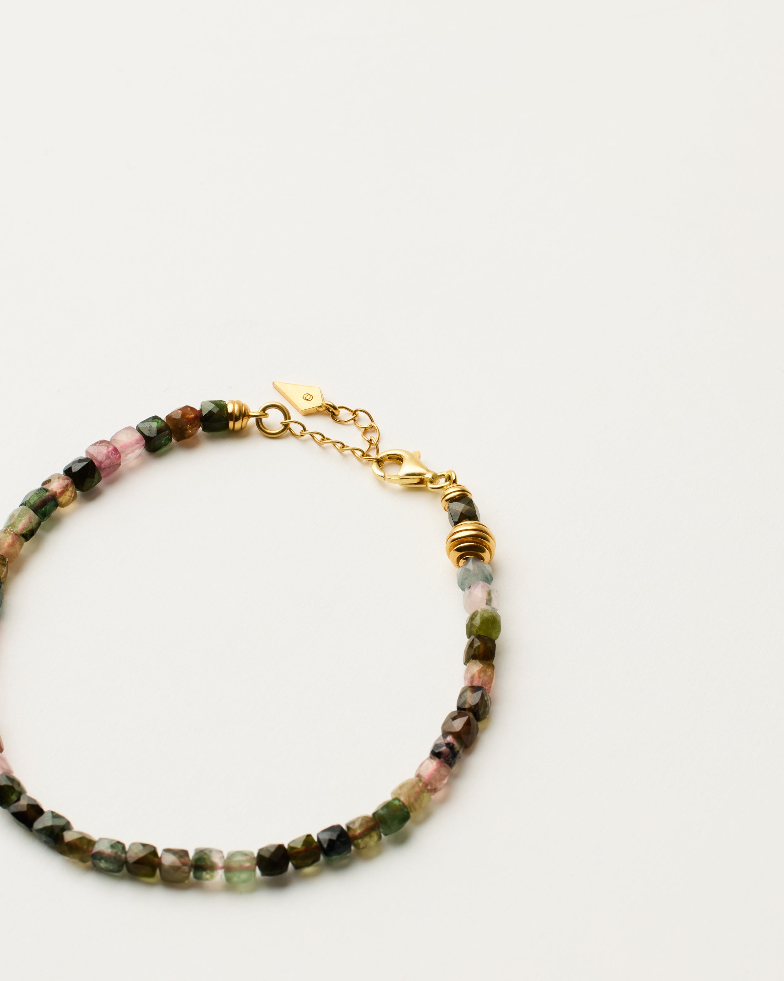 ETERNA AURIL Tourmaline bracelet with polished gold-plated silver spiral bead, 4 cm extension chain and clasp, arrowhead-shaped fantasy signature, and 4 mm faceted tourmaline bead strand.