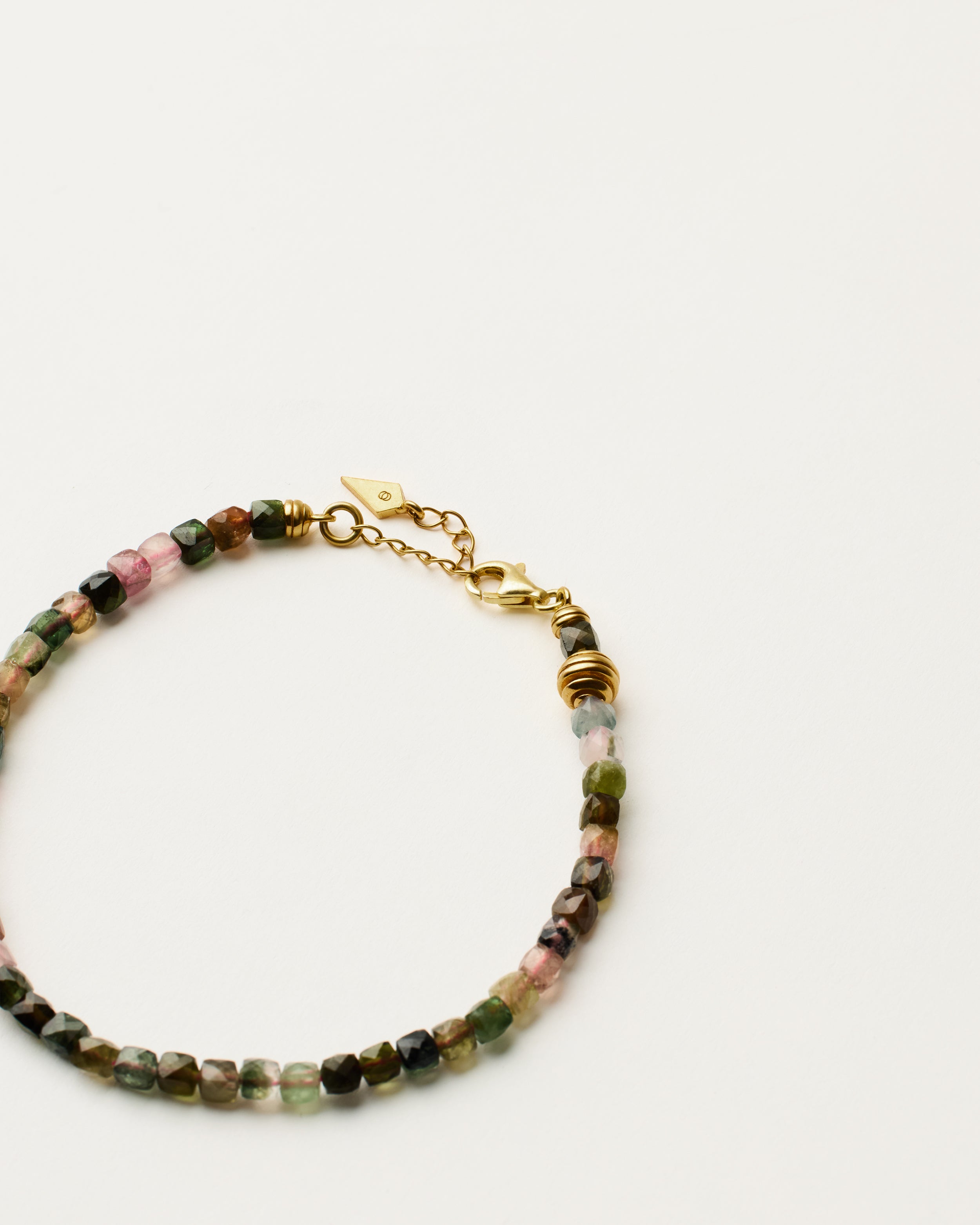 ETERNA AURIL Tourmaline bracelet with polished gold spiral bead, 4 cm extension chain and clasp, arrowhead-shaped fantasy signature, and 4 mm faceted tourmaline bead strand.
