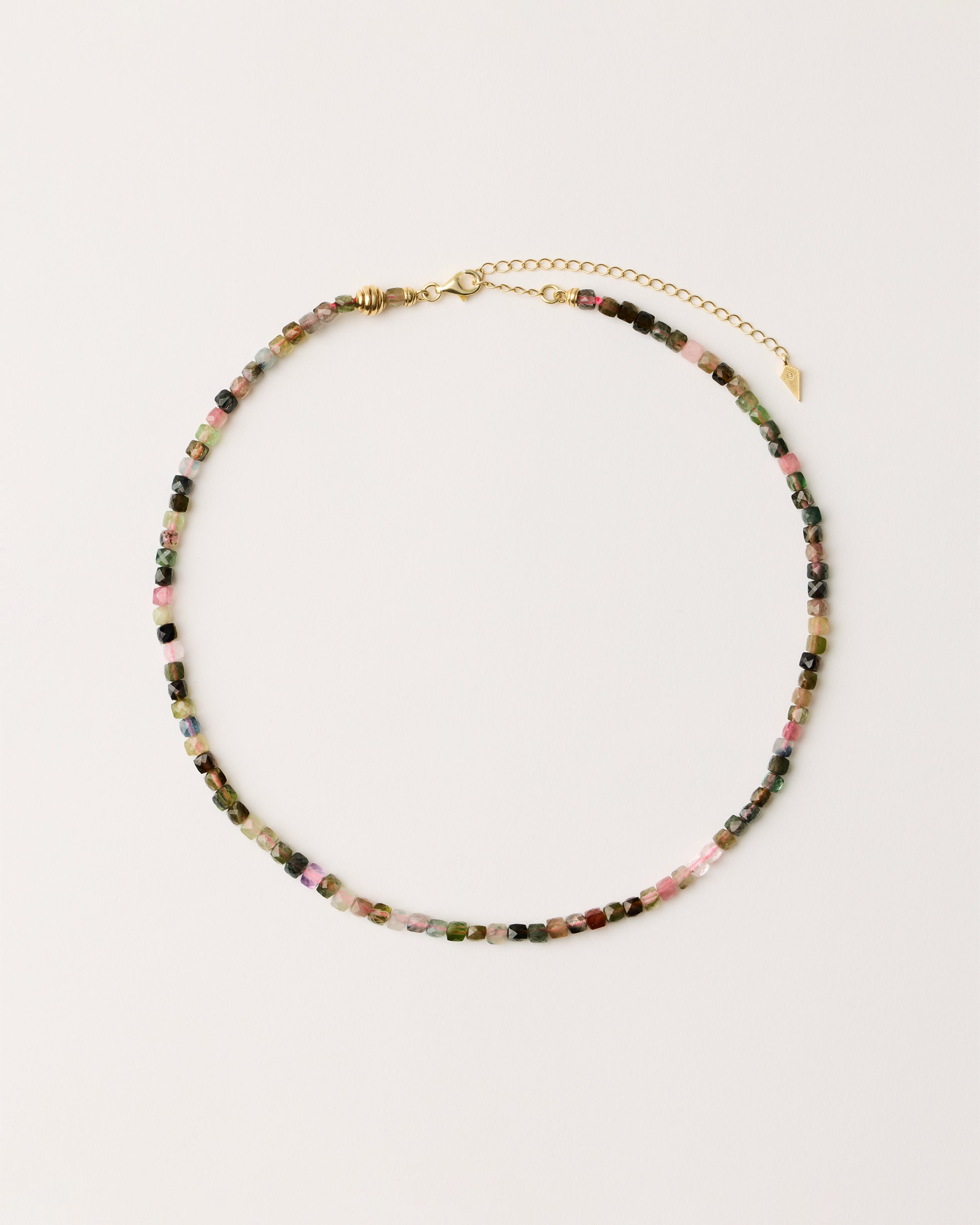 ETERNA AURIL Tourmaline necklace with polished gold spiral bead, 8 cm extension chain and clasp, arrowhead-shaped fantasy signature, and 4 mm faceted tourmaline bead strand.