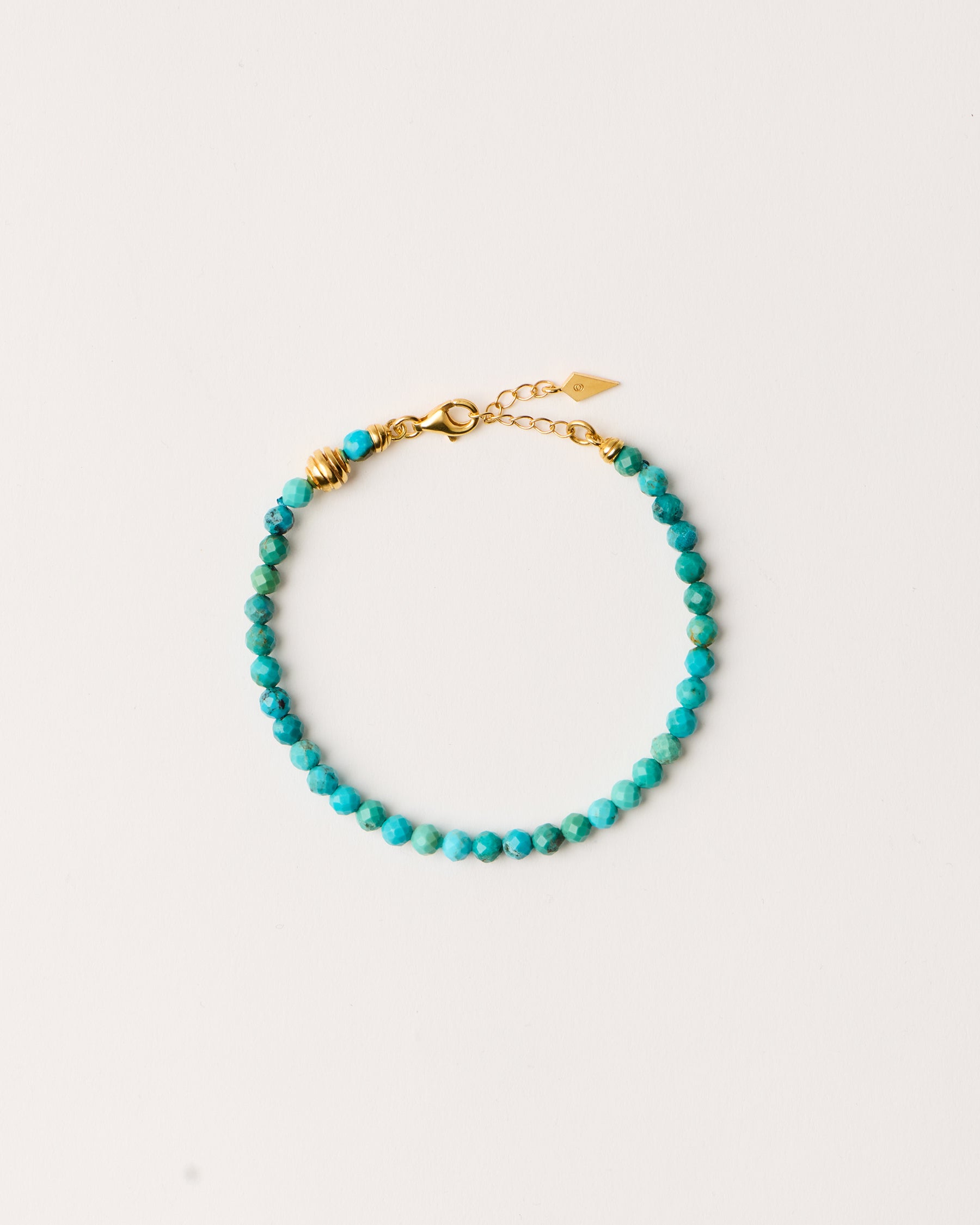 ETERNA AZURA Turquoise bracelet with polished gold-plated silver spiral bead, 4 cm extension chain and clasp, arrowhead-shaped fantasy signature, and 4 mm faceted turquoise bead strand.