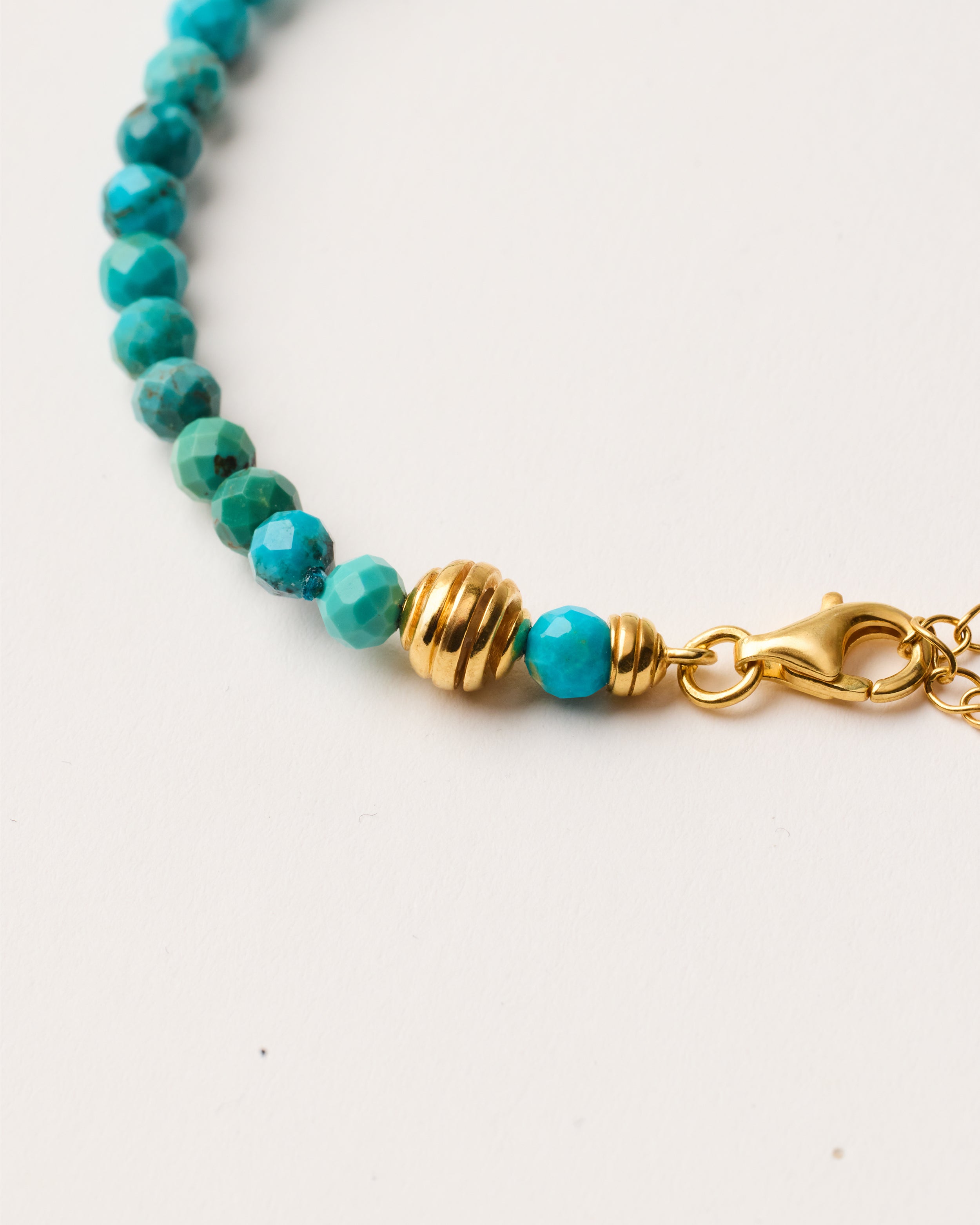 ETERNA AZURA Turquoise bracelet with polished gold-plated silver spiral bead, 4 cm extension chain and clasp, arrowhead-shaped fantasy signature, and 4 mm faceted turquoise bead strand.