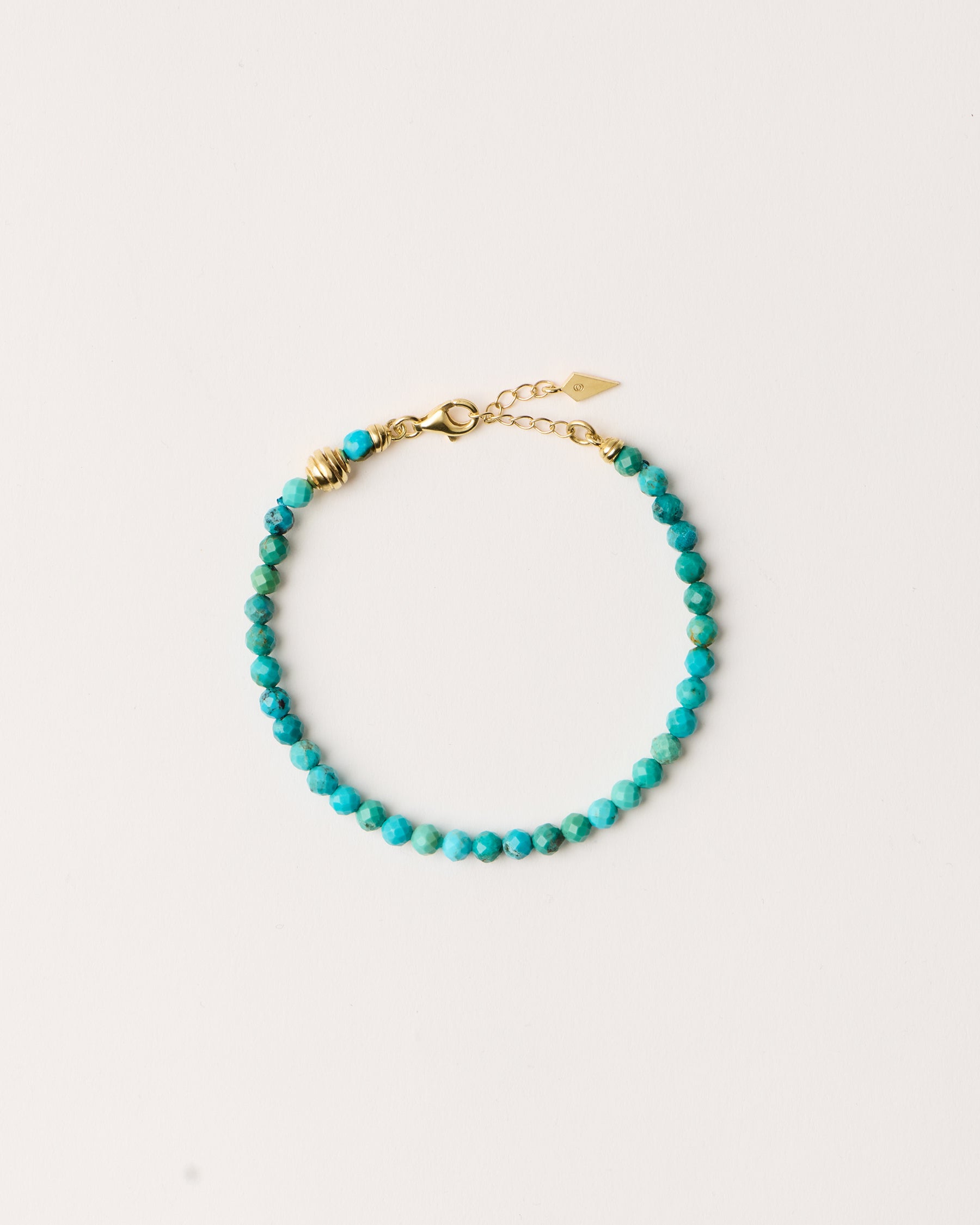 ETERNA AZURA Turquoise bracelet with polished gold spiral bead, 4 cm extension chain and clasp, arrowhead-shaped fantasy signature, and 4 mm faceted turquoise bead strand.