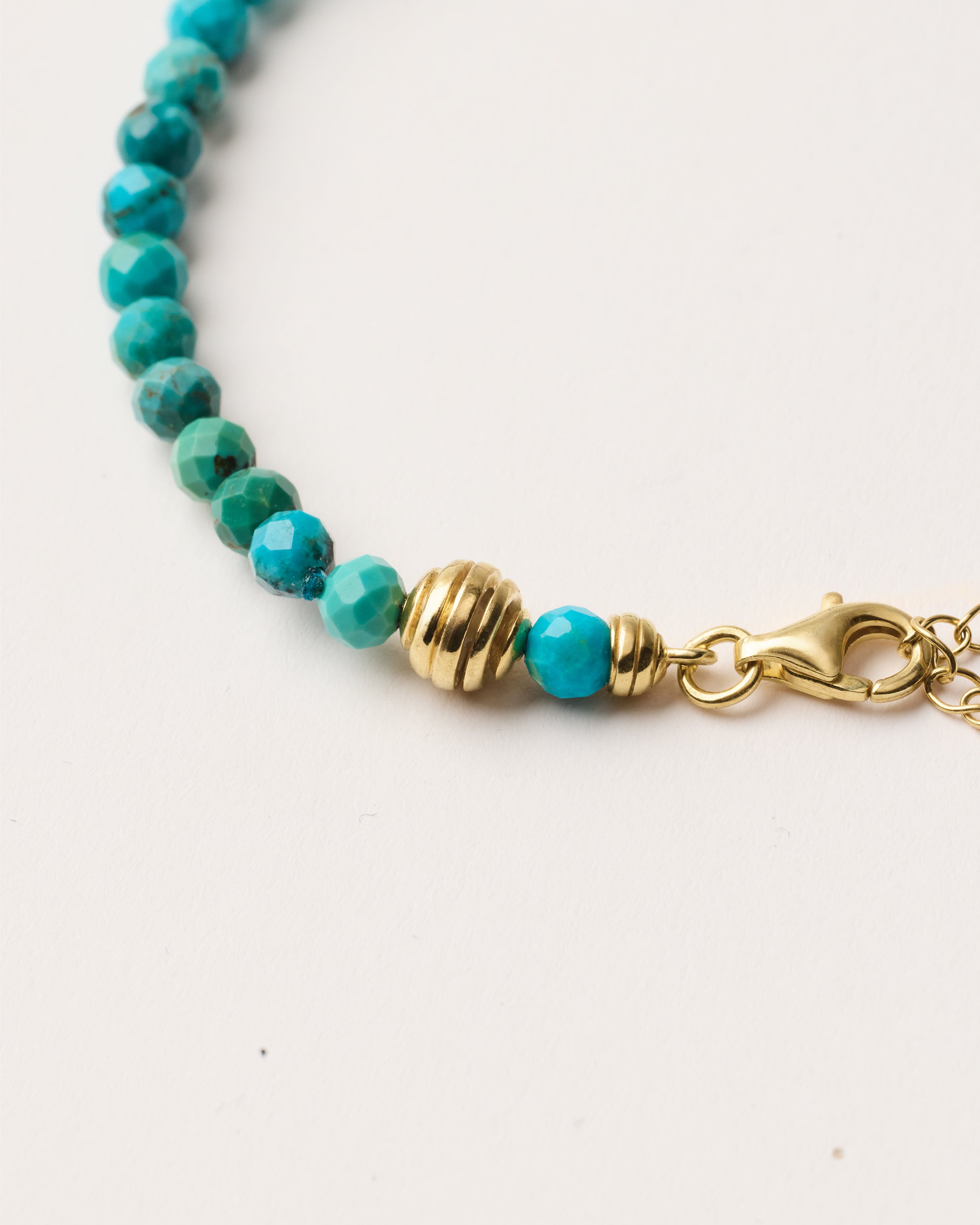 ETERNA AZURA Turquoise bracelet with polished gold spiral bead, 4 cm extension chain and clasp, arrowhead-shaped fantasy signature, and 4 mm faceted turquoise bead strand.