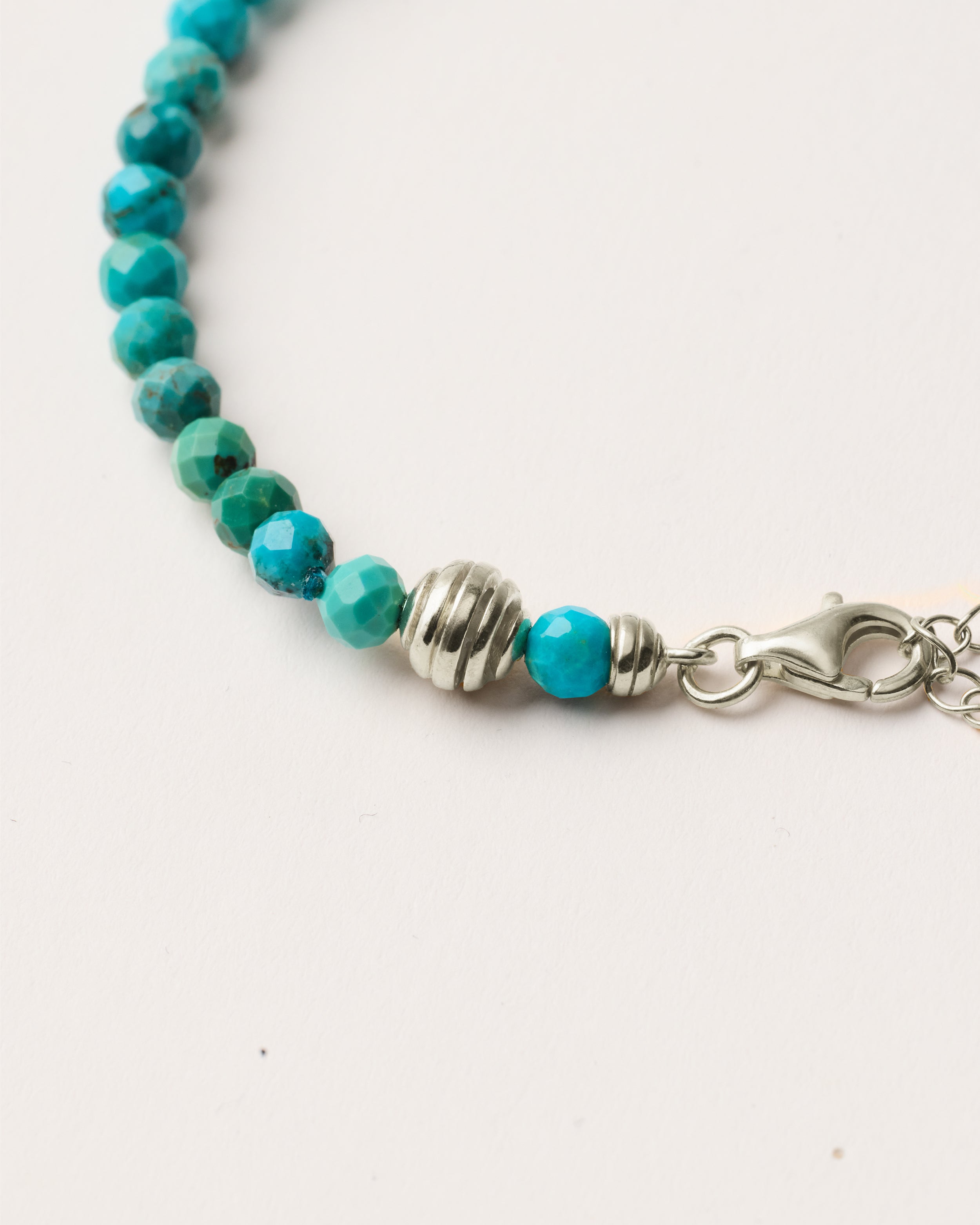 ETERNA AZURA Turquoise bracelet with polished silver spiral bead, 4 cm extension chain and clasp, arrowhead-shaped fantasy signature, and 4 mm faceted turquoise bead strand.