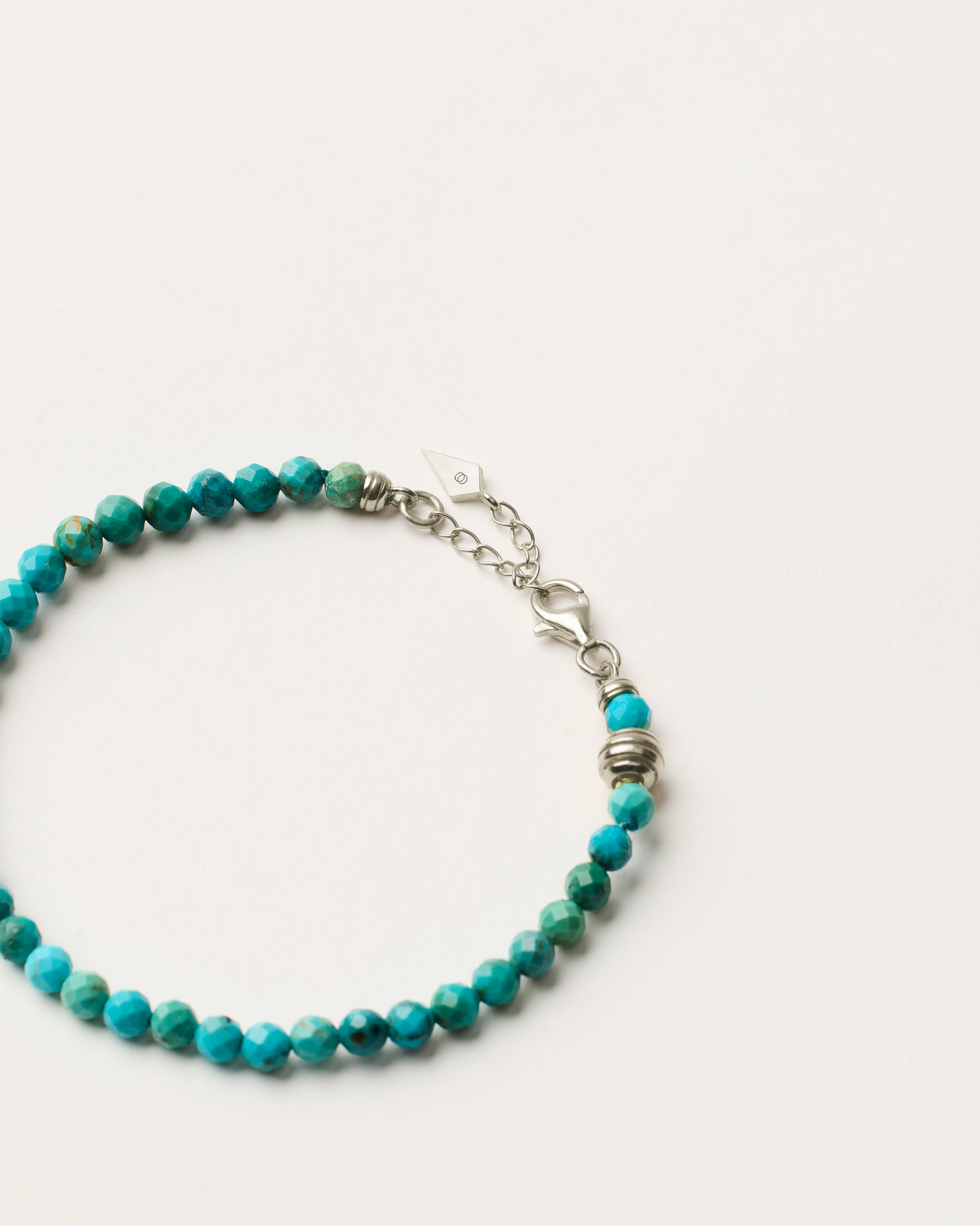 ETERNA AZURA Turquoise bracelet with polished silver spiral bead, 4 cm extension chain and clasp, arrowhead-shaped fantasy signature, and 4 mm faceted turquoise bead strand.