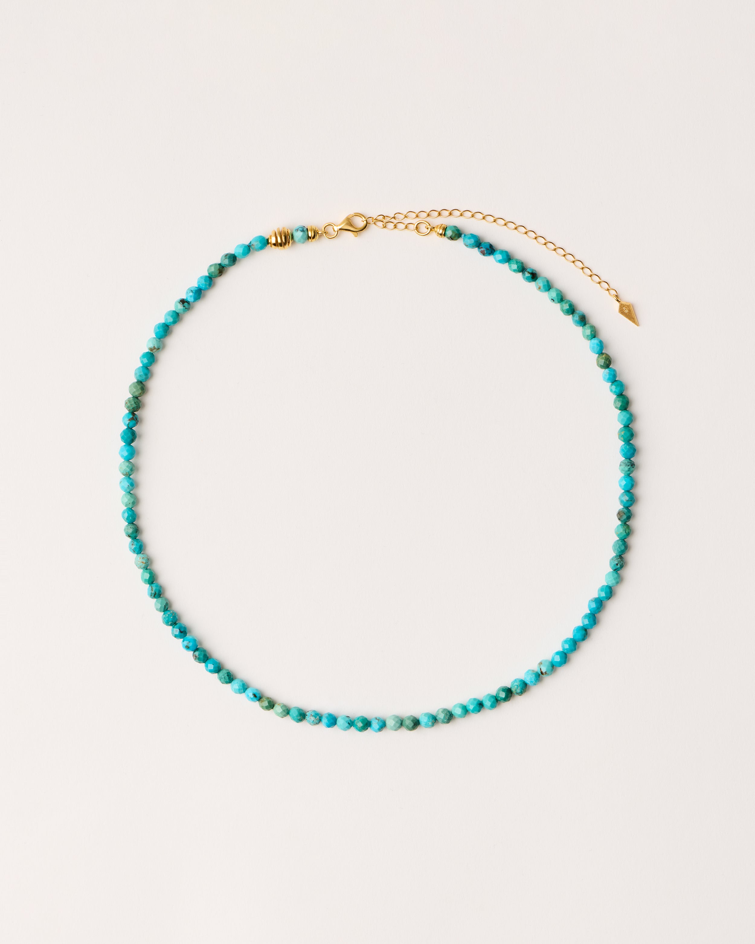 ETERNA AZURA Turquoise necklace with polished gold-plated silver spiral bead, 8 cm extension chain and clasp, arrowhead-shaped fantasy signature, and 4 mm faceted turquoise bead strand.