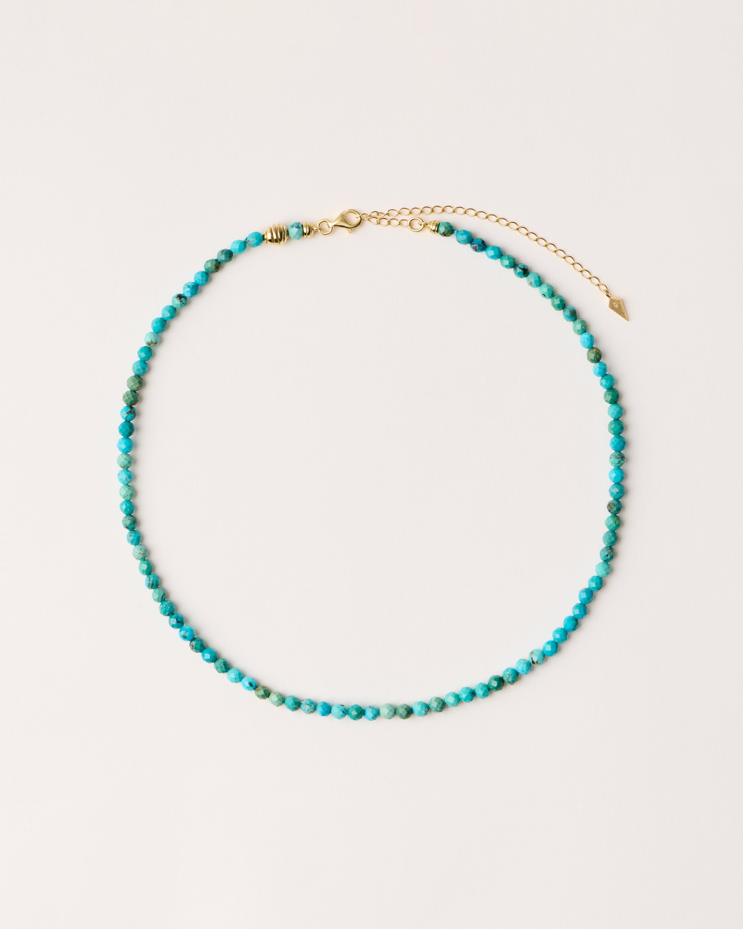 ETERNA AZURA Turquoise necklace with polished gold spiral bead, 8 cm extension chain and clasp, arrowhead-shaped fantasy signature, and 4 mm faceted turquoise bead strand.