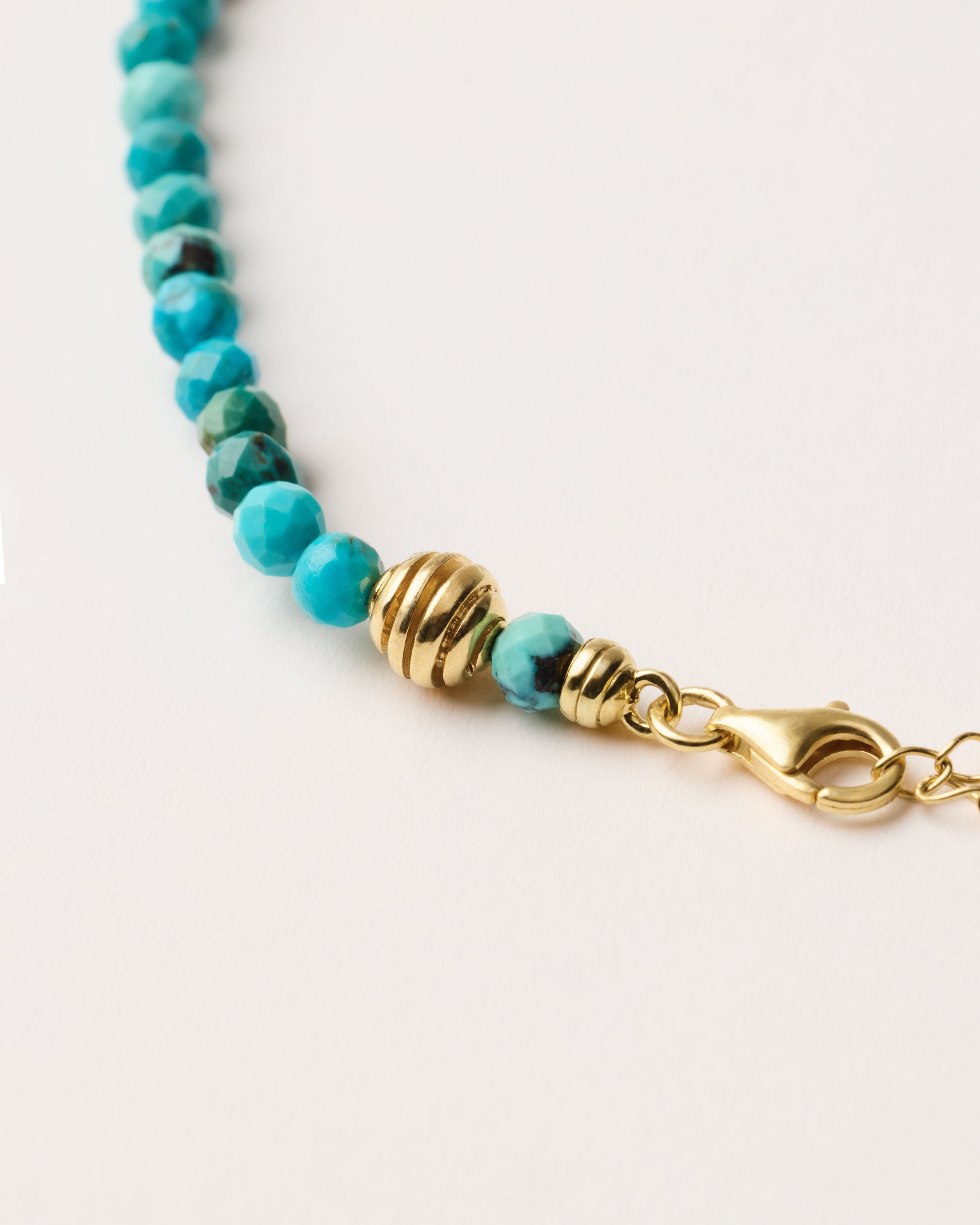 ETERNA AZURA Turquoise necklace with polished gold spiral bead, 8 cm extension chain and clasp, arrowhead-shaped fantasy signature, and 4 mm faceted turquoise bead strand.