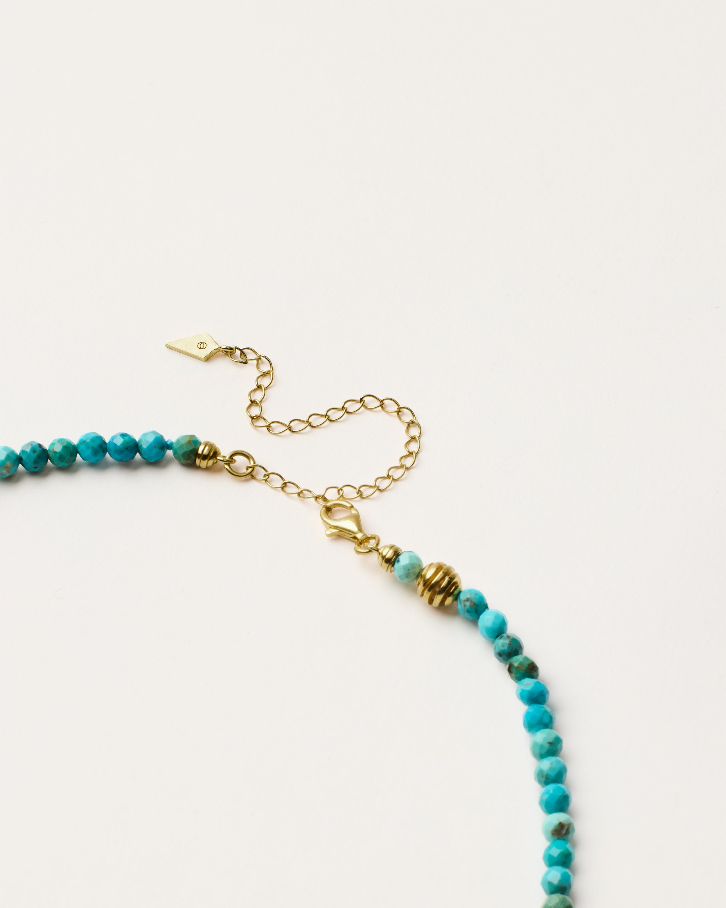 ETERNA AZURA Turquoise necklace with polished gold spiral bead, 8 cm extension chain and clasp, arrowhead-shaped fantasy signature, and 4 mm faceted turquoise bead strand.