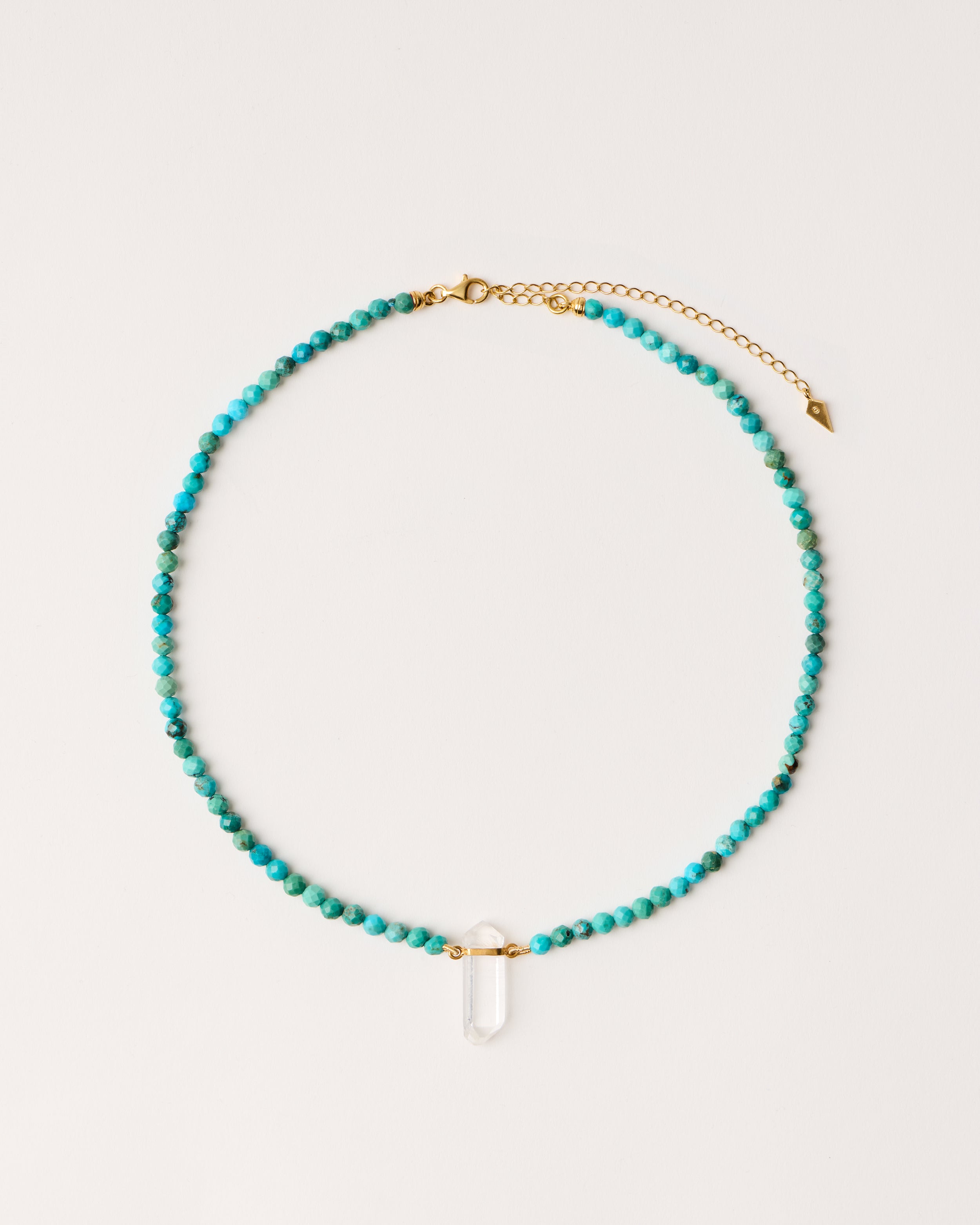 ENCARA AZURA Turquoise necklace with raw polished quartz point pendant, gold-plated silver 8 cm extension chain and clasp, arrowhead-shaped fantasy signature, and 4 mm faceted turquoise bead strand.