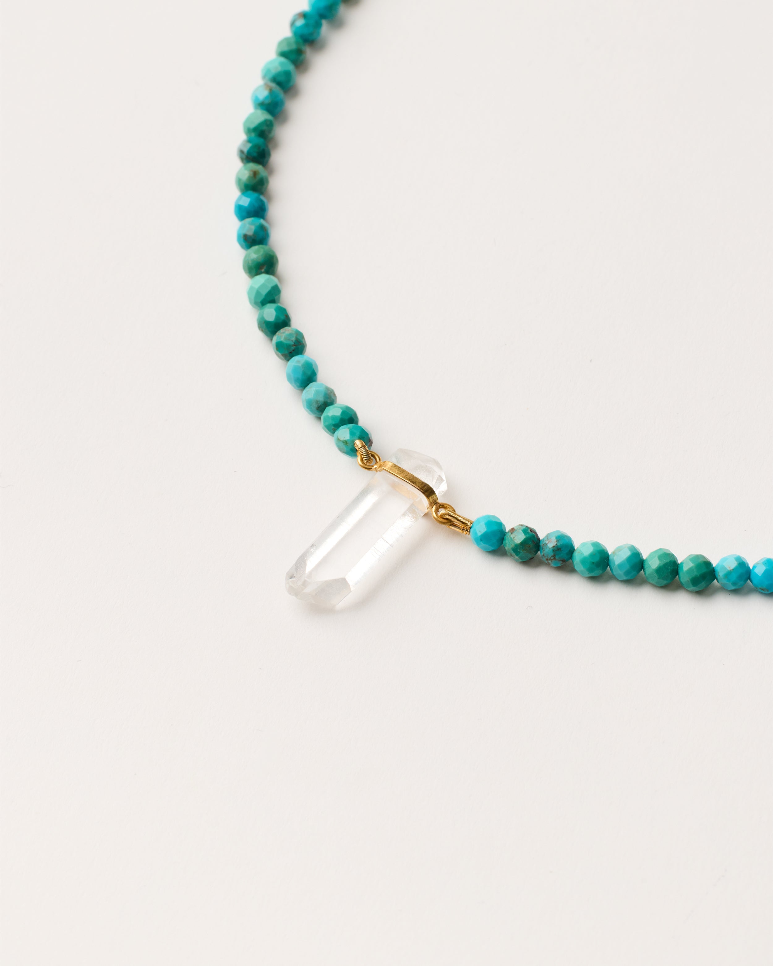ENCARA AZURA Turquoise necklace with raw polished quartz point pendant, gold-plated silver 8 cm extension chain and clasp, arrowhead-shaped fantasy signature, and 4 mm faceted turquoise bead strand.