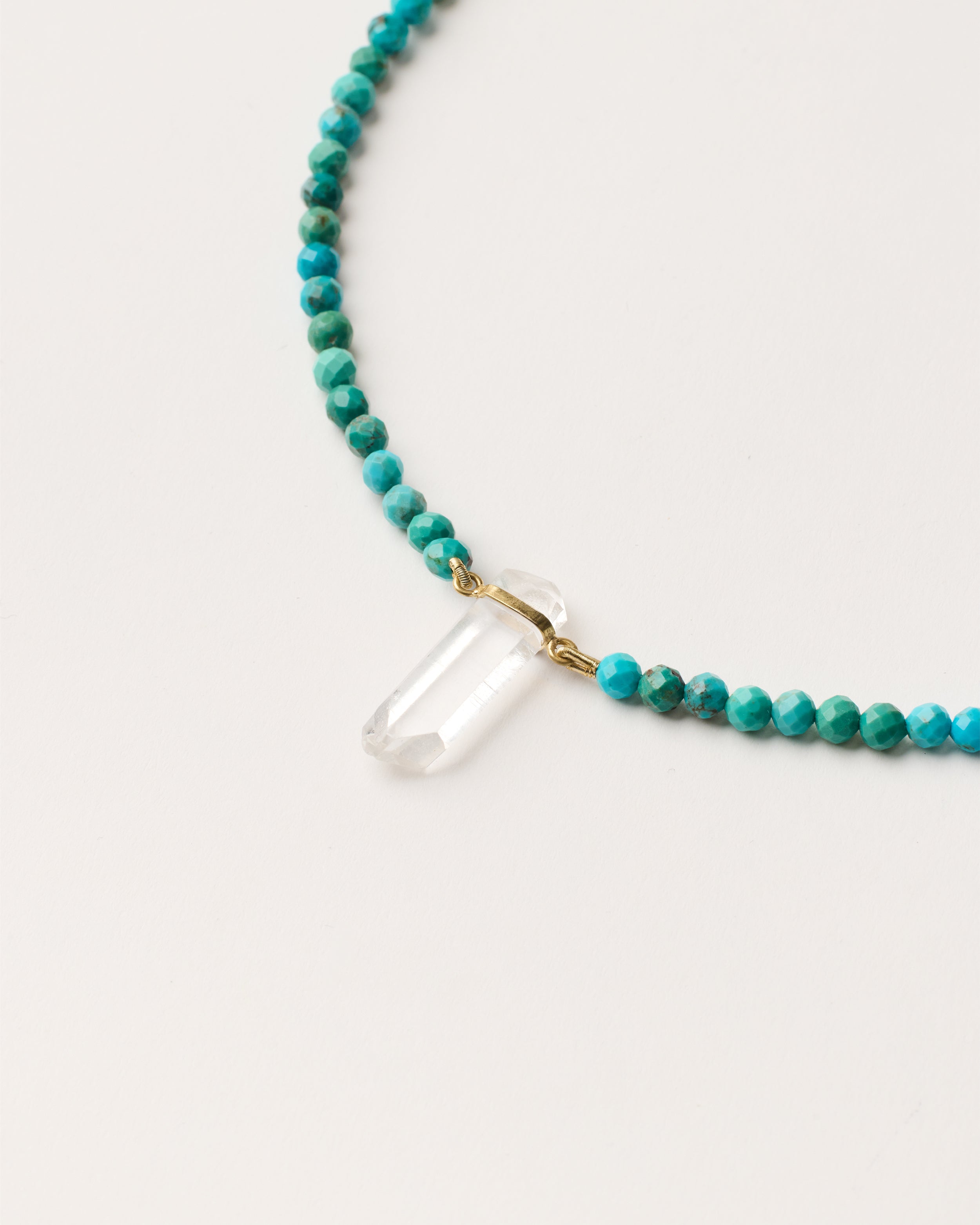 ENCARA AZURA Turquoise necklace with raw polished quartz point pendant, gold 8 cm extension chain and clasp, arrowhead-shaped fantasy signature, and 4 mm faceted turquoise bead strand.