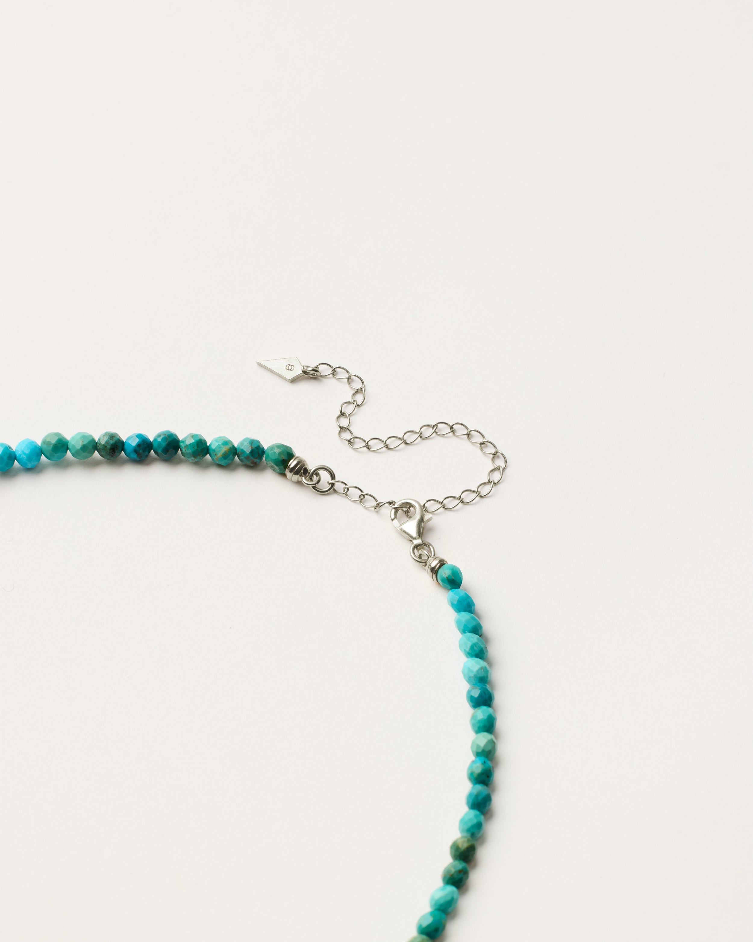 ENCARA AZURA Turquoise necklace with raw polished quartz point pendant, silver 8 cm extension chain and clasp, arrowhead-shaped fantasy signature, and 4 mm faceted turquoise bead strand.